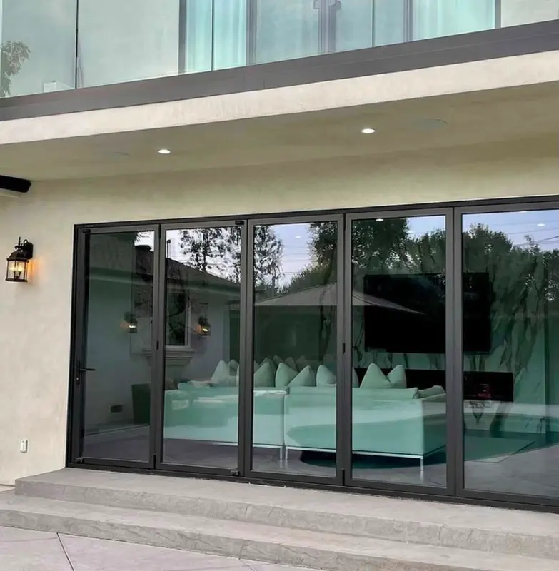 Ventanal plegable de vidrio y aluminio hacia un living con vista a la pileta