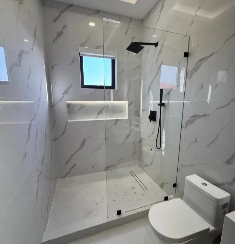 Mampara de ducha frameless en baño de mármol con esquinero