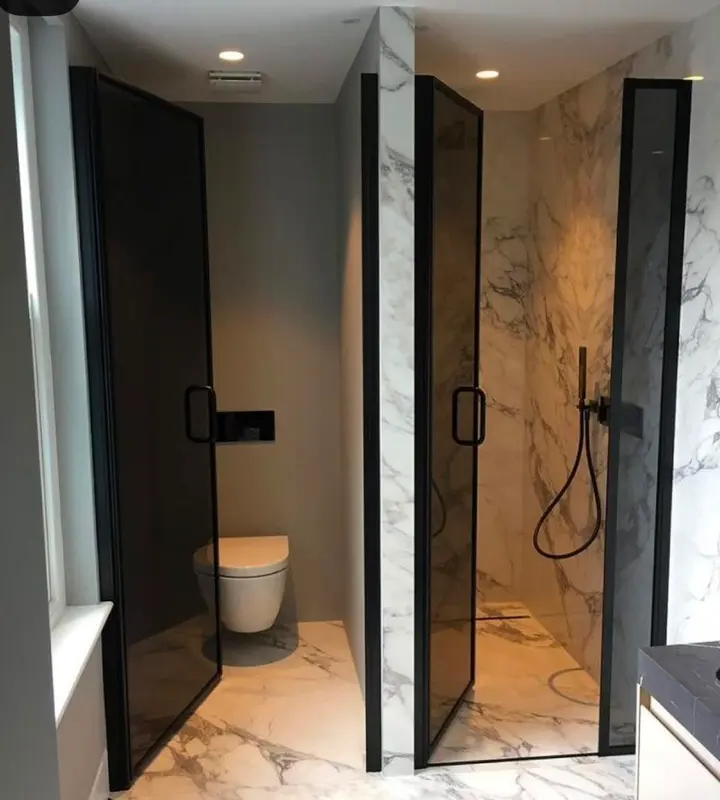 Dos mamparas de vidrio con marco negro en baños en suite